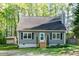 Charming home featuring gray siding, black shutters, and a wooden staircase leading to the front door at 2700 Ross Rd, Durham, NC 27703