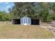 Blue outbuilding featuring covered wings and a gated perimeter on a lush, grassy lot at 283 Raynor Rd, Spring Lake, NC 28390