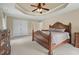 Well-lit main bedroom featuring a tray ceiling, carpet, and elegant furnishings with a closet at 3 Haycox Ct, Durham, NC 27713