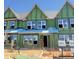 Townhome under construction showcasing windows, green weather barrier, and ladders against a bright blue sky at 3020 White Rail Dr, Fuquay Varina, NC 27526