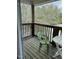 Cozy wooden balcony featuring a green chair and a small white table overlooking trees at 303 Smith Level Rd # E32, Chapel Hill, NC 27516