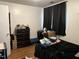 Modest bedroom featuring hardwood floors, large window with dark curtain, and a dark dresser at 303 Smith Level Rd # E32, Chapel Hill, NC 27516