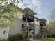 Apartment building featuring multiple private balconies, neutral-toned siding, and neatly trimmed landscaping, set amongst mature trees at 303 Smith Level Rd # E32, Chapel Hill, NC 27516