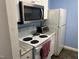 Compact kitchen featuring white appliances, including a microwave and stove, set against blue walls and light countertops at 303 Smith Level Rd # E32, Chapel Hill, NC 27516