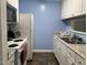 Functional kitchen with white appliances, white cabinetry, and granite-look countertops, complemented by blue walls and tiled floors at 303 Smith Level Rd # E32, Chapel Hill, NC 27516