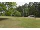 Large, grassy backyard with mature trees and two outbuildings at the edge of the yard at 3121 Blue Hill Ln, Durham, NC 27703