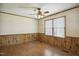 Spacious bedroom with ceiling fan, wood paneled walls, wood floors, and natural light from two windows at 3121 Blue Hill Ln, Durham, NC 27703