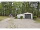 View of backyard outbuildings showing gravel drive and mature trees at 3121 Blue Hill Ln, Durham, NC 27703