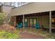 Covered stone patio with blue chairs and sliding glass doors overlooking wooded area at 33 Stoneridge Cir, Durham, NC 27705