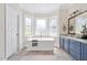 Bright bathroom features a soaking tub, tile flooring, blue vanity, and white trim at 40 Farrells Creek Rd, Apex, NC 27523