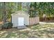 Outbuilding with white door, surrounded by lush greenery and a basketball hoop beyond a wooden fence at 40 Farrells Creek Rd, Apex, NC 27523