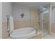 Bathroom featuring a soaking tub, glass enclosed shower and tan tile at 400 W North St # 1420, Raleigh, NC 27603