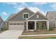 Charming single-Gathering home with a stone and gray shingle facade, two-car garage, and welcoming front porch at 421 Raven Cliff St, Apex, NC 27523