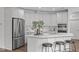 Modern kitchen featuring white cabinets, stainless steel appliances, a center island, and stylish stools at 421 Raven Cliff St, Apex, NC 27523
