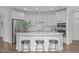 Bright kitchen with white cabinets, stainless steel appliances, a center island, and modern stools at 421 Raven Cliff St, Apex, NC 27523