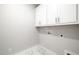 Bright laundry room featuring ample white cabinetry, tiled floors, and neutral-toned walls at 4897 Grosbeak Ct, Mebane, NC 27302