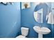 Charming half-bathroom with blue walls, a pedestal sink, round mirror, and a toilet, offering a convenient powder room at 509 Rose Creek Ct, Zebulon, NC 27597