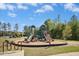 Community playground with slides and climbing structures surrounded by lush greenery under a partly cloudy sky at 509 Rose Creek Ct, Zebulon, NC 27597
