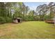 Sprawling backyard with green grass, a shed, and tall mature trees along the back at 545 Irvan St, Clayton, NC 27520