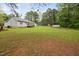 This backyard showcases the home's deck, storage shed, and a large, grassy area surrounded by mature trees at 545 Irvan St, Clayton, NC 27520