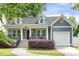 Charming home exterior with blue siding, covered front porch, manicured shrubs, and attached one-car garage at 604 Mills St, Raleigh, NC 27608