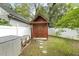 Backyard featuring a wooden shed, white privacy fence, and partial view of the neighboring house at 604 Mills St, Raleigh, NC 27608