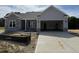New construction featuring a two-car garage, stone accents and gray vinyl siding, with an unfinished yard at 69 Tee Dr, Selma, NC 27576