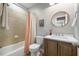 Clean bathroom with tiled shower, modern vanity, and stylish round mirror at 725 Ancient Oaks Dr, Holly Springs, NC 27540