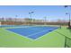 Outdoor tennis court complex featuring blue and green court with lighting for nighttime play at 725 Ancient Oaks Dr, Holly Springs, NC 27540