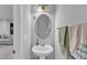 A powder room with a pedestal sink, oval mirror, light fixture, and a view to the living room at 8601 Red Canyon Way, Raleigh, NC 27616