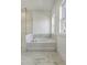 Modern bathtub with marble style trim, framed windows, and sleek frameless shower next to the tub at 964 Double Helix Rd, Apex, NC 27523