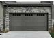 Attached garage door with stone accents, exterior light fixture, and concrete driveway at 964 Double Helix Rd, Apex, NC 27523