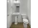 Compact powder room featuring a pedestal sink, toilet, and modern fixtures with wood-look floors at 964 Double Helix Rd, Apex, NC 27523