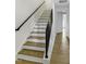 Staircase with wood treads, white risers, and a modern black railing leading to an open hallway at 964 Double Helix Rd, Apex, NC 27523