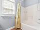 Well-lit bathtub and shower with white fixtures, window, and neutral walls at 1012 Trail Stream Way, Knightdale, NC 27545