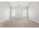 A cozy bedroom with neutral walls, carpet, ceiling fan, and two windows at 1012 Trail Stream Way, Knightdale, NC 27545