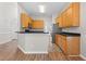 Open kitchen with wooden cabinets, stainless steel appliances, and a breakfast bar on wood-look floors at 1012 Trail Stream Way, Knightdale, NC 27545