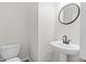 A half bathroom with a toilet and pedestal sink featuring a black faucet and round mirror at 104 Rosebud Ln, Durham, NC 27704