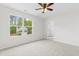 Bright bedroom with a ceiling fan, a large window overlooking the trees, and neutral carpeting at 104 Rosebud Ln, Durham, NC 27704