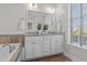 Bathroom featuring double sink vanity, soaking tub, and natural light from the window at 10410 Sablewood Dr # 111, Raleigh, NC 27617