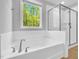 Modern bathroom with a soaking tub and a separate glass-enclosed shower and view to the outside at 105 Scoville Rd, Garner, NC 27529