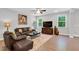 Inviting living room featuring wood floors, large windows, brown leather furniture, and modern decor at 105 Scoville Rd, Garner, NC 27529