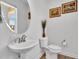 Well-lit powder room featuring pedestal sink, round mirror, wood floors and decorative accents at 105 Scoville Rd, Garner, NC 27529