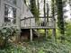 The back porch features railings and a table and chairs, all surrounded by trees and ground cover at 106 Orchard Rd, Henderson, NC 27536