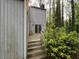 Back porch with steps, a sliding glass door, and surrounding green bushes and trees at 106 Orchard Rd, Henderson, NC 27536
