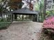 Large brick carport offers ample space and is surrounded by lush greenery and beautiful flowers at 106 Orchard Rd, Henderson, NC 27536