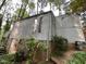 Side view of home shows brick base and wooden exterior surrounded by trees and landscaping at 106 Orchard Rd, Henderson, NC 27536