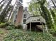 Back of home with brick chimney and a wooden back porch surrounded by trees and ground cover at 106 Orchard Rd, Henderson, NC 27536