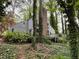 The back of the house shows a brick chimney and a wooden back porch surrounded by trees and ground cover at 106 Orchard Rd, Henderson, NC 27536