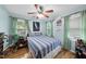 Bright bedroom with hardwood floors, a striped comforter, a ceiling fan, and natural light from the windows at 108 Ridgepath Way, Cary, NC 27511